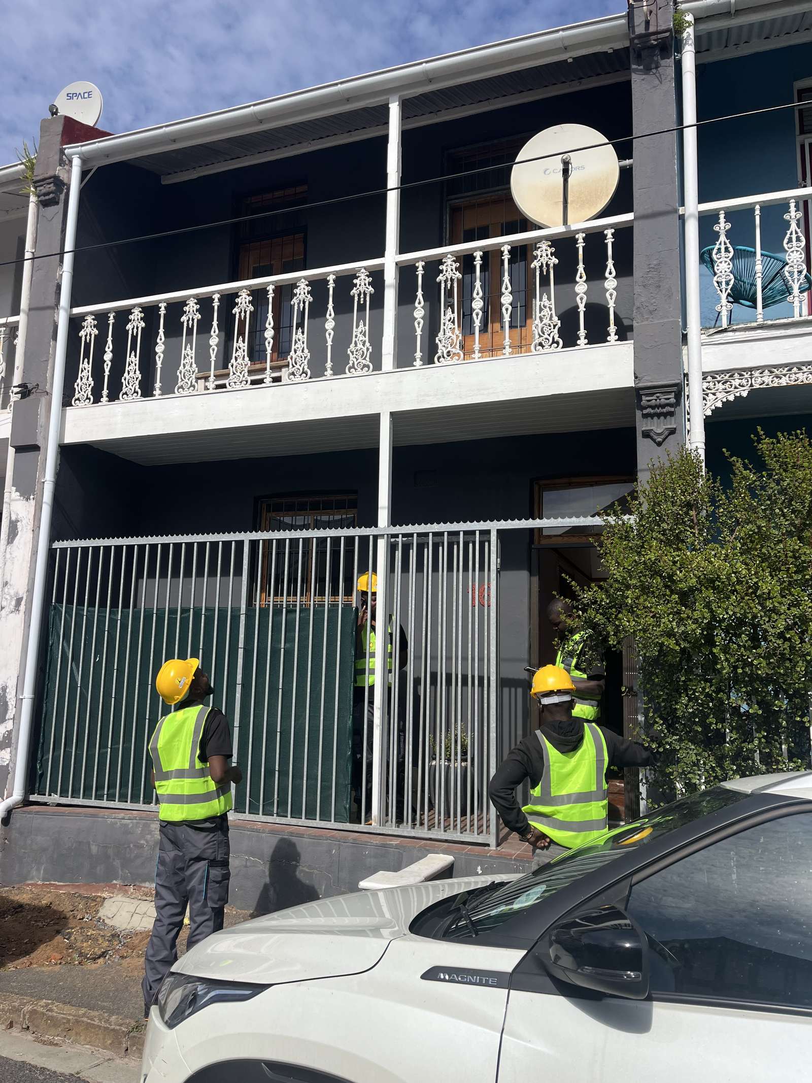 Sundial Solar installers in hi-vis and hard hats arriving at a Victorian terrace house on a Cape Town street