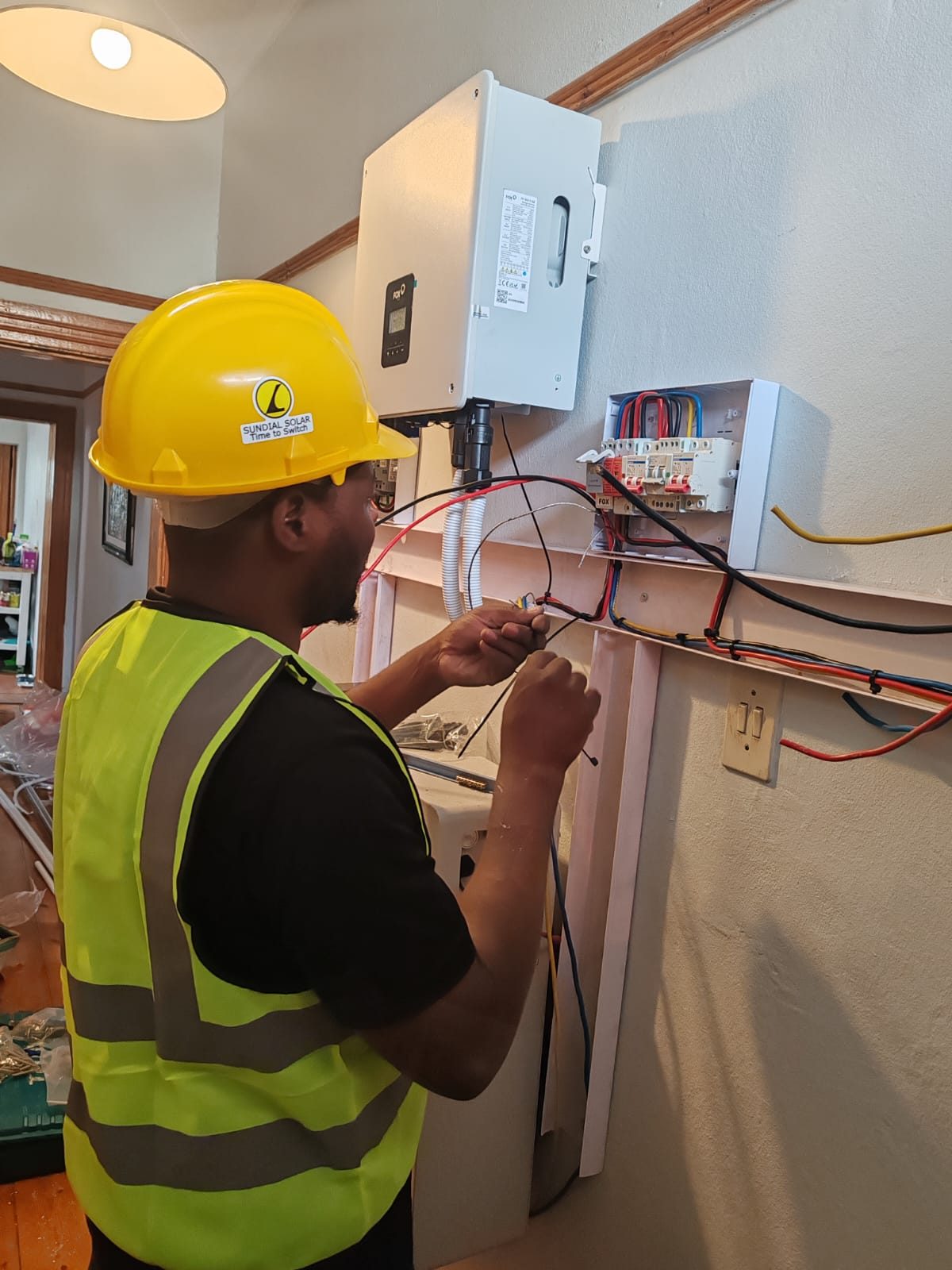 Installer making AC connections next to the inverter in a hallway of a Victorian home